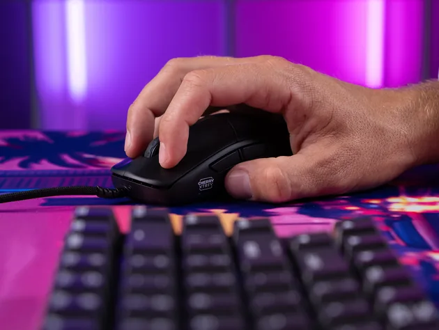 Hand using the actual CHERRY XTRFY M42V2 on a gaming mouse pad