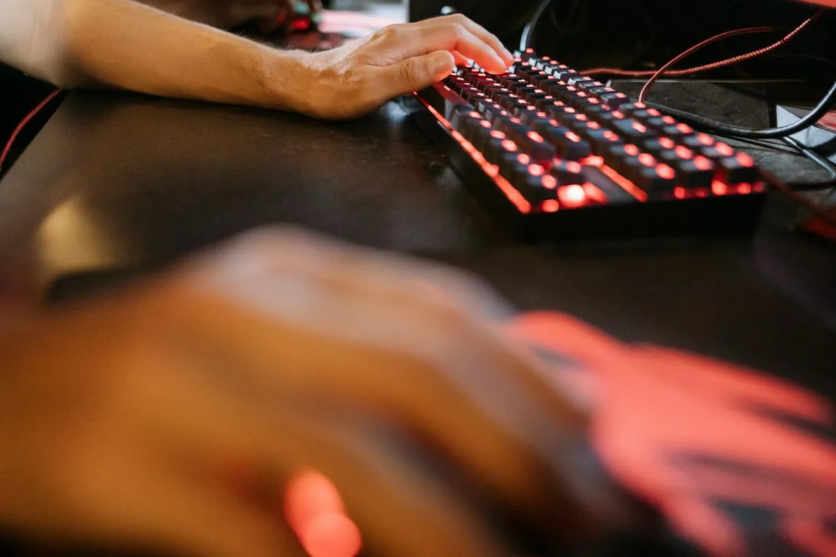 Hands on a backlit gaming keyboard and mouse, illustrating hardware DPI versus software sensitivity