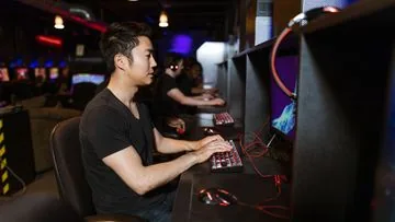 Focused PC gamer at desktop monitors in a gaming venue
