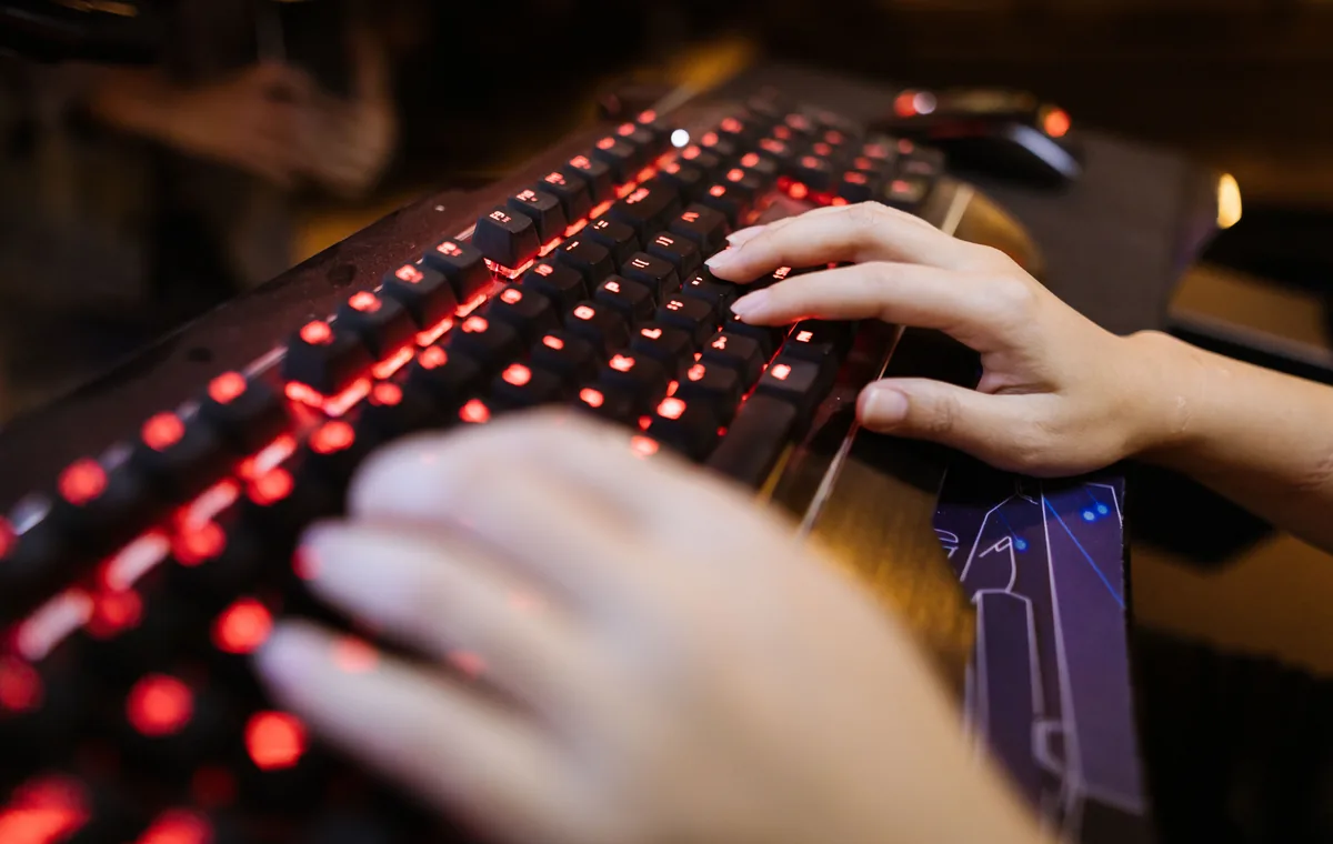 Tangan mengetik di keyboard backlit saat mengecek konsistensi bunyi tombol