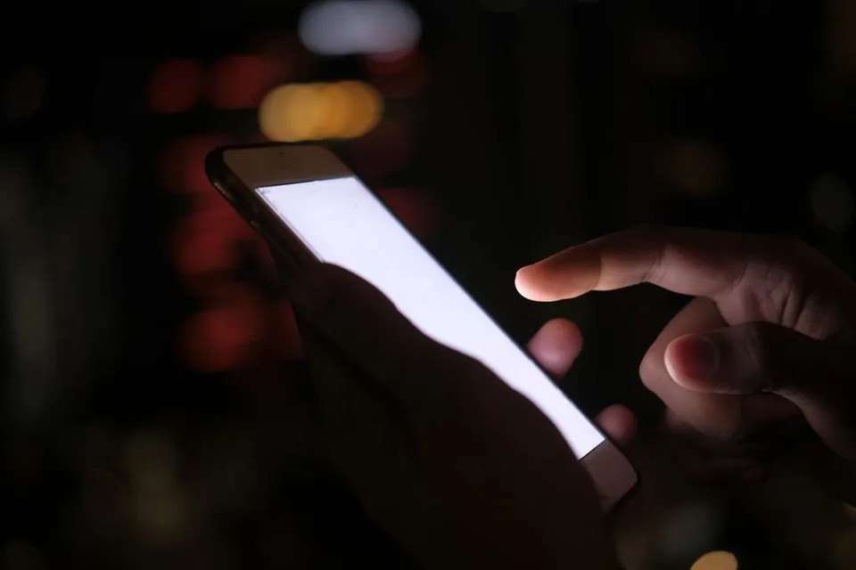 Fingertip tapping the bright screen of a smartphone in a dark room during a browser vibration check