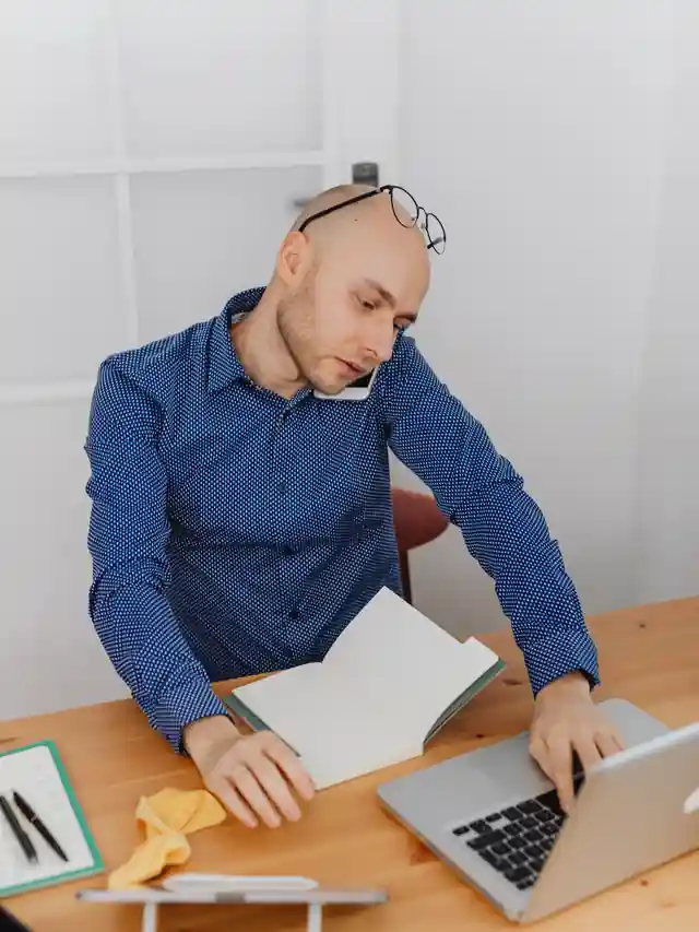 Illustrative stock photo of a man working between a laptop, notebook and phone