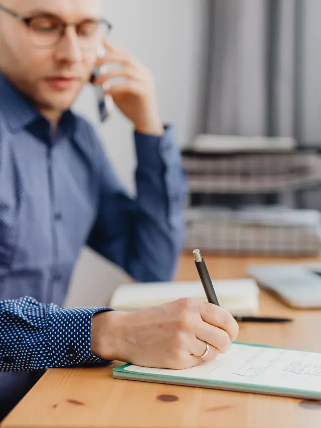 Illustrative stock photo of a man writing a plan during a phone call