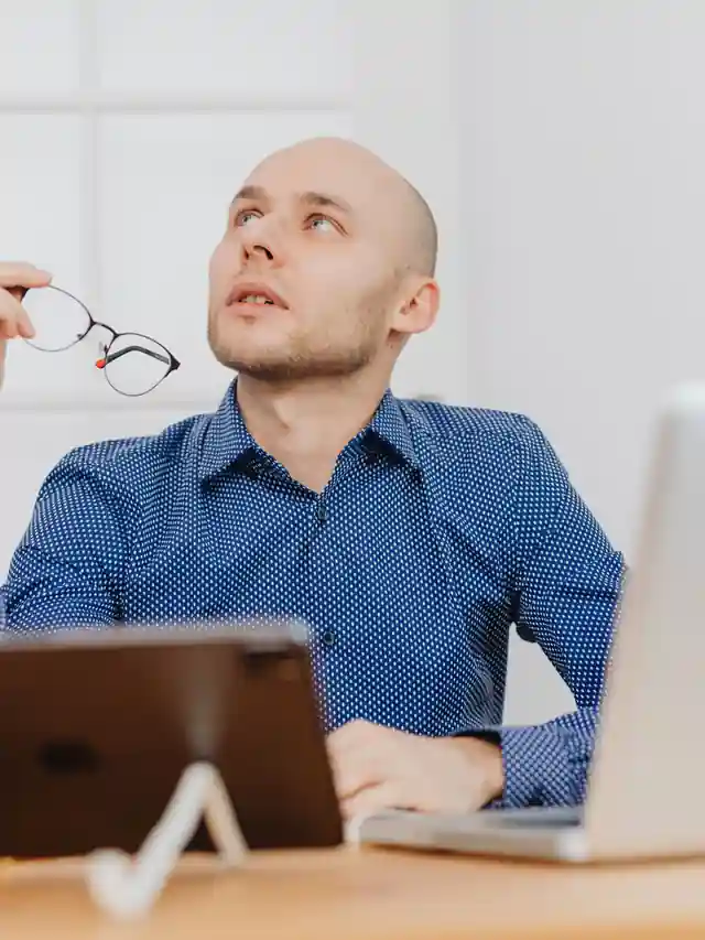 Illustrative stock photo of a man thinking while holding his eyeglasses