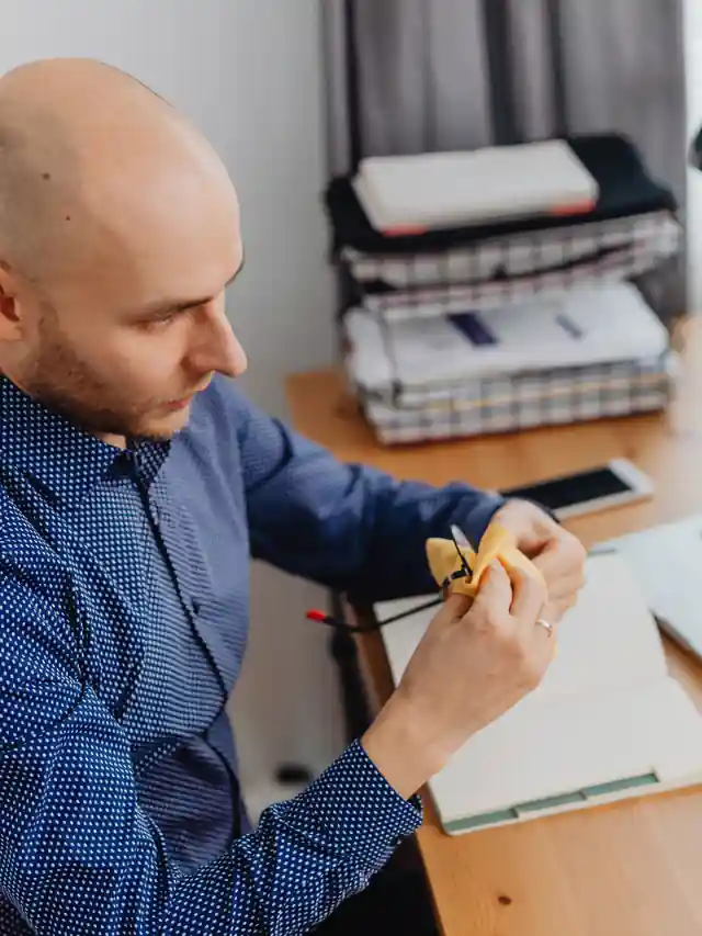 Illustrative stock photo of a man reviewing work documents beside a laptop
