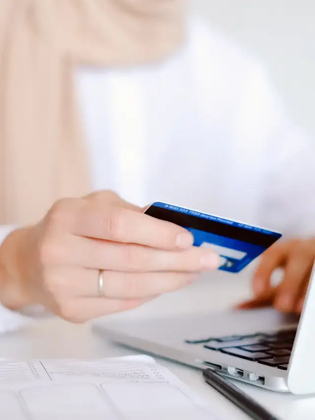 Person checking compatibility details on a laptop while holding a card