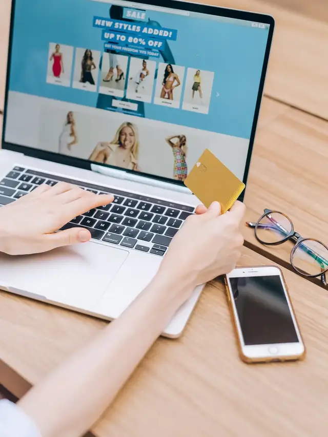 Online shopper comparing products on a laptop while holding a card
