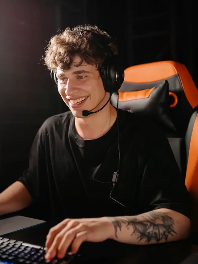 The curly-haired gamer smiling while using a keyboard and mouse; illustrative stock, not a measured weapon test