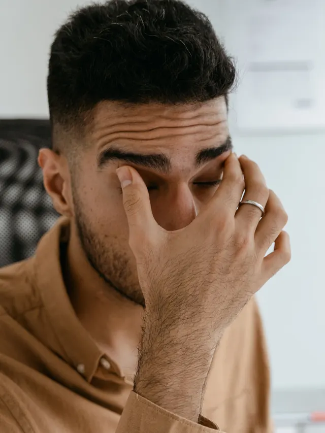 Close-up of a man rubbing his tired eyes in an office