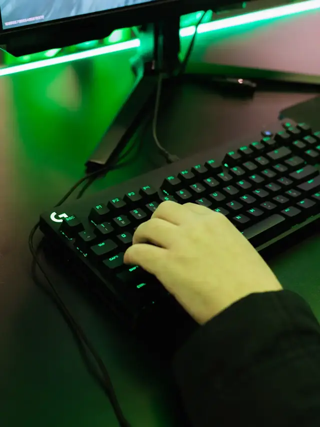Hand holding a real gaming chord on a green-lit keyboard