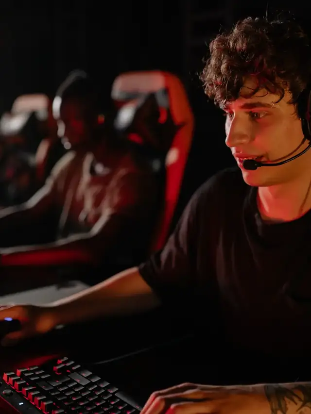 Focused esports player pressing a keyboard in a dark gaming arena