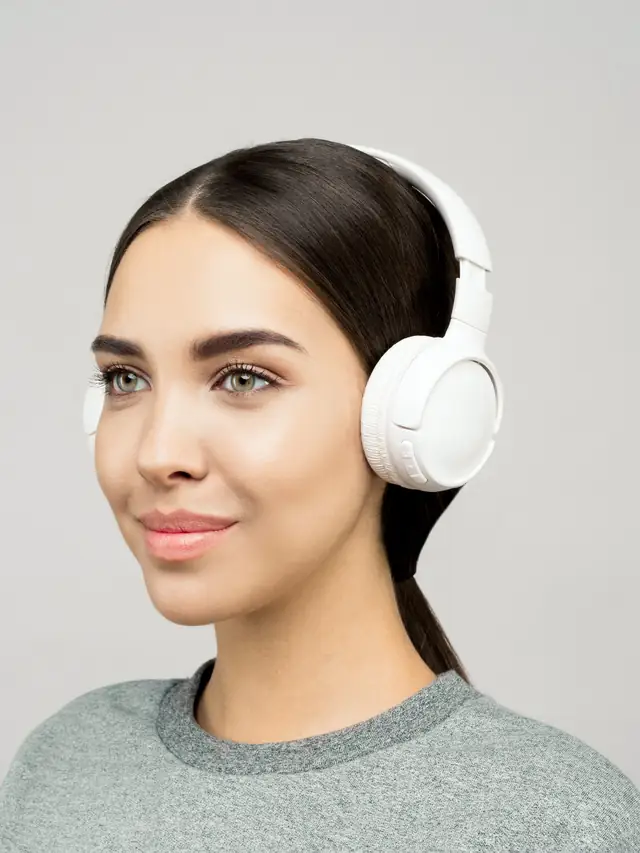 Smiling woman enjoying music through white headphones