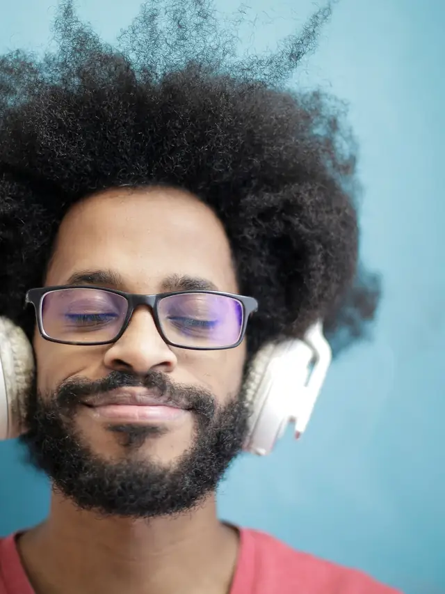 Man with afro hair listening to music with his eyes closed