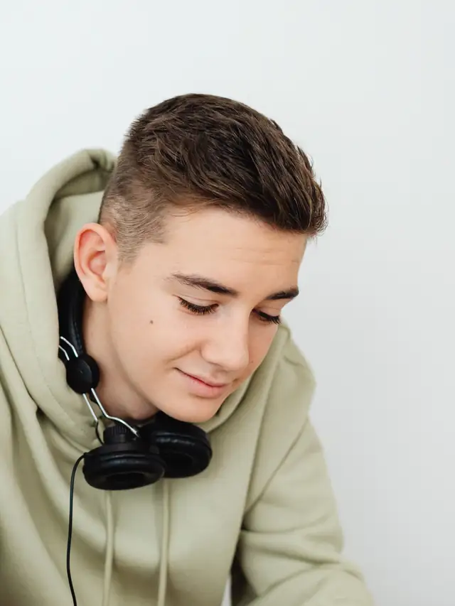 Young man in a hoodie wearing headphones and looking down