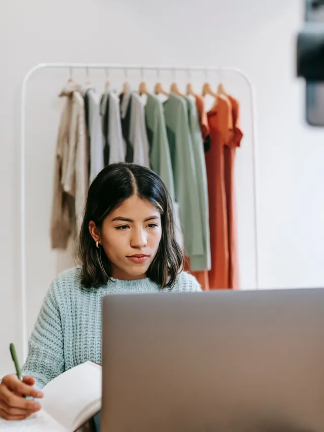 Woman reviewing notes beside a laptop