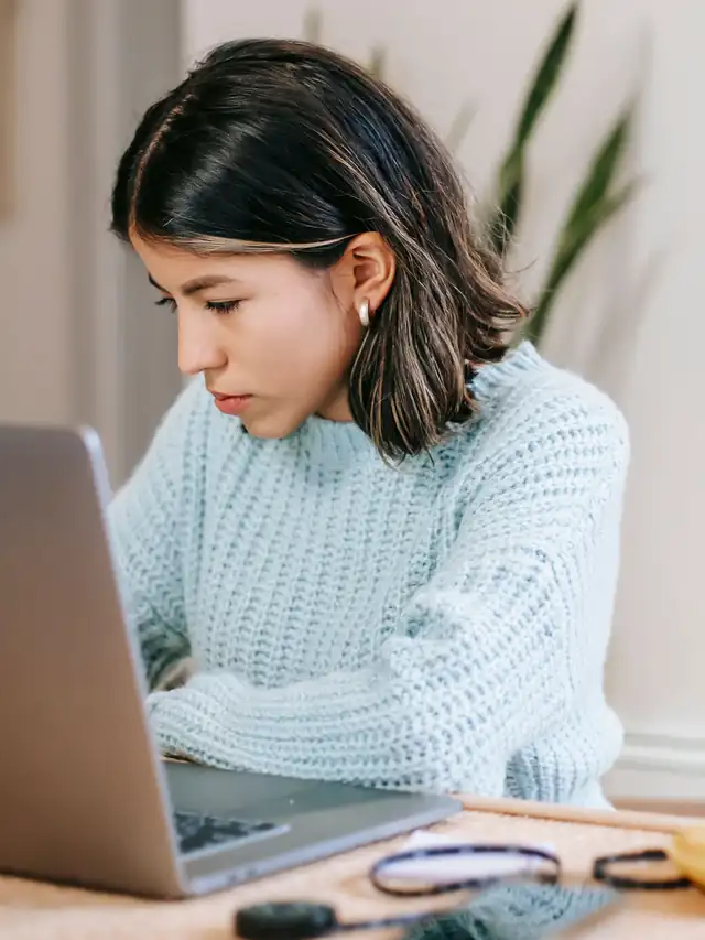 Woman looking down while working on a laptop