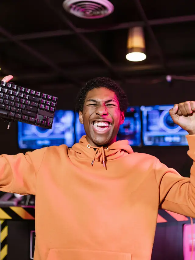 Excited man celebrating while holding a compact keyboard overhead