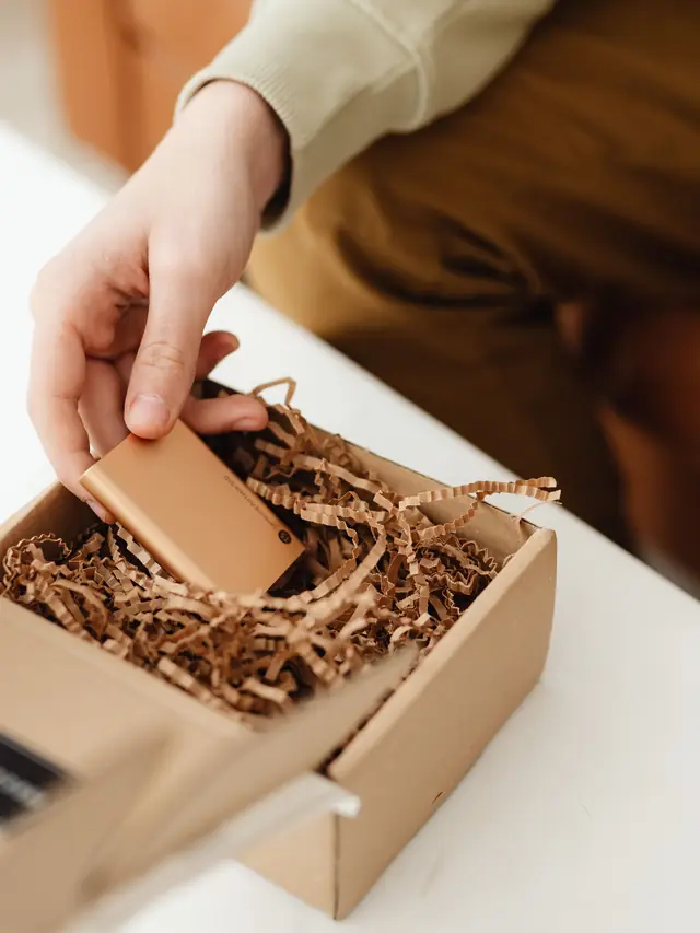Person lifting a small gadget out of a cardboard delivery box