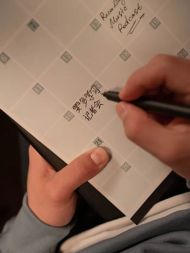 Hand marking a monthly calendar with a thumb resting beside the date 21