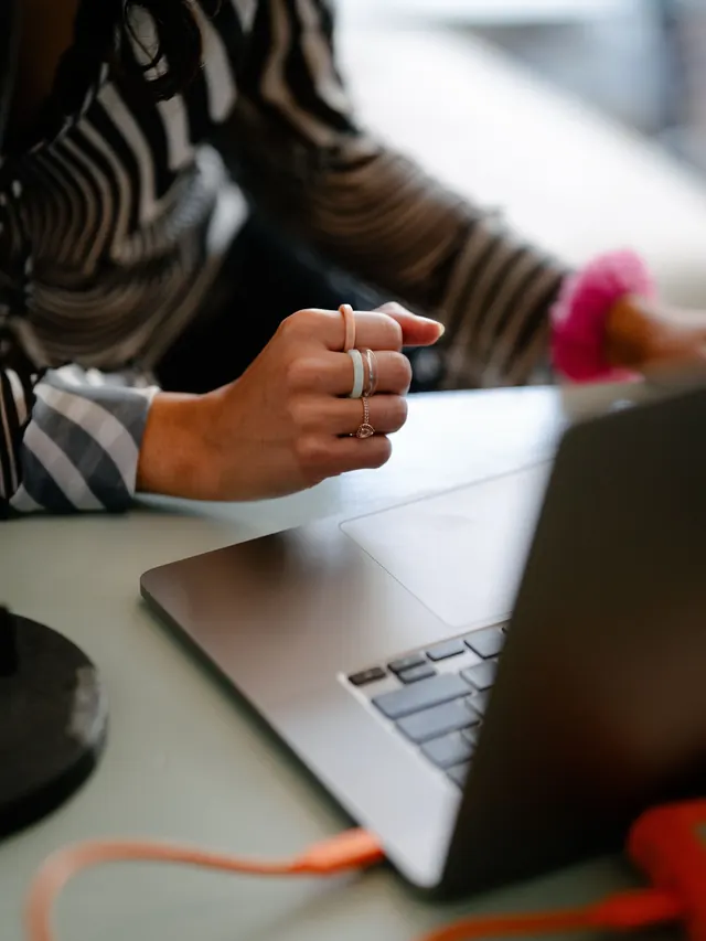 Woman working at a laptop with a USB cable visibly connected