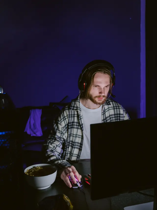 Plaid-shirt gamer testing controls at a desktop computer