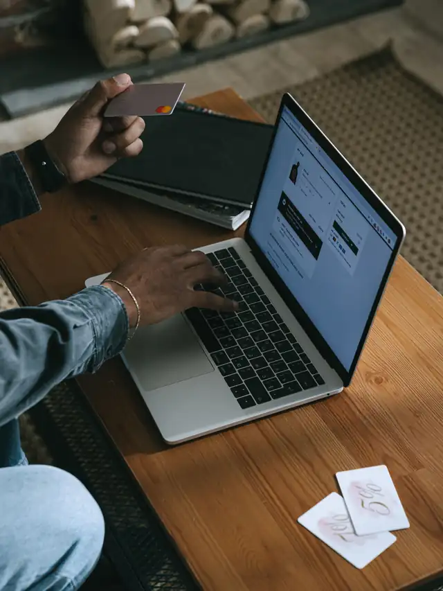 Person holding a payment card while shopping on a laptop