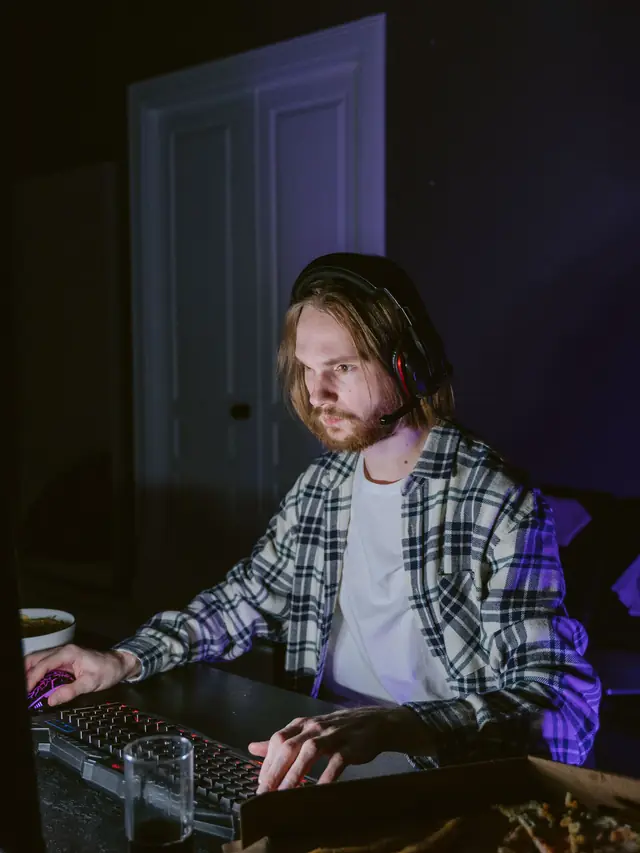 Plaid-shirt gamer using a keyboard and mouse while wearing a headset