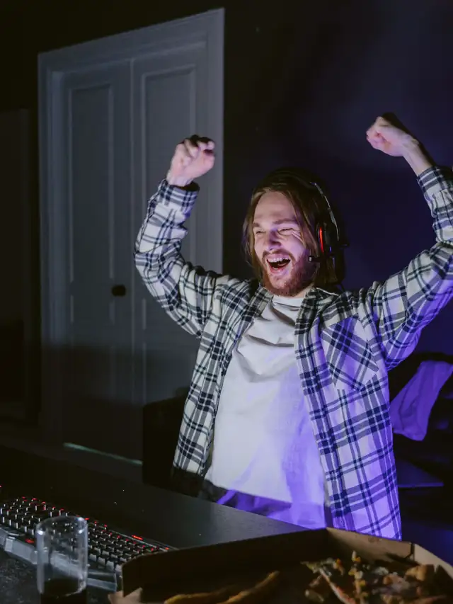 Plaid-shirt gamer celebrating after using a keyboard at a desk
