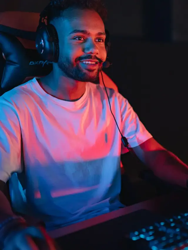 Bearded player in a white T-shirt smiling at his keyboard in neon light, ready to run a browser test