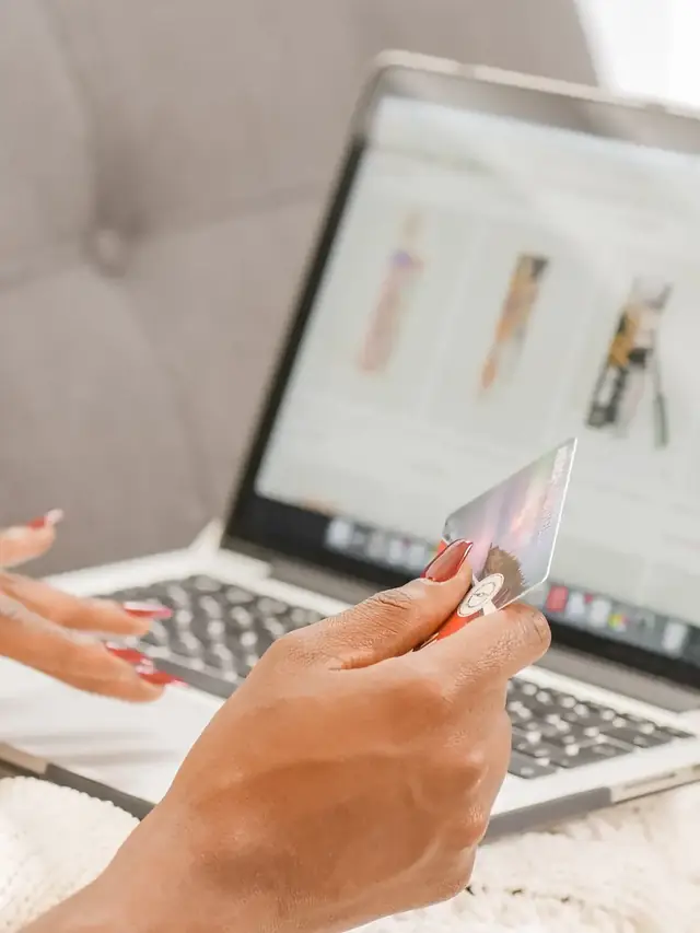 Person reading purchase terms while holding a payment card at a laptop