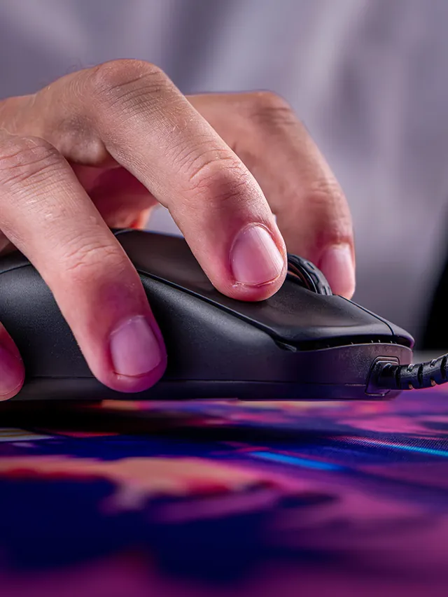 Close-up of a hand gripping the CHERRY XTRFY M42V2 on a desk mat with the braided cable visible