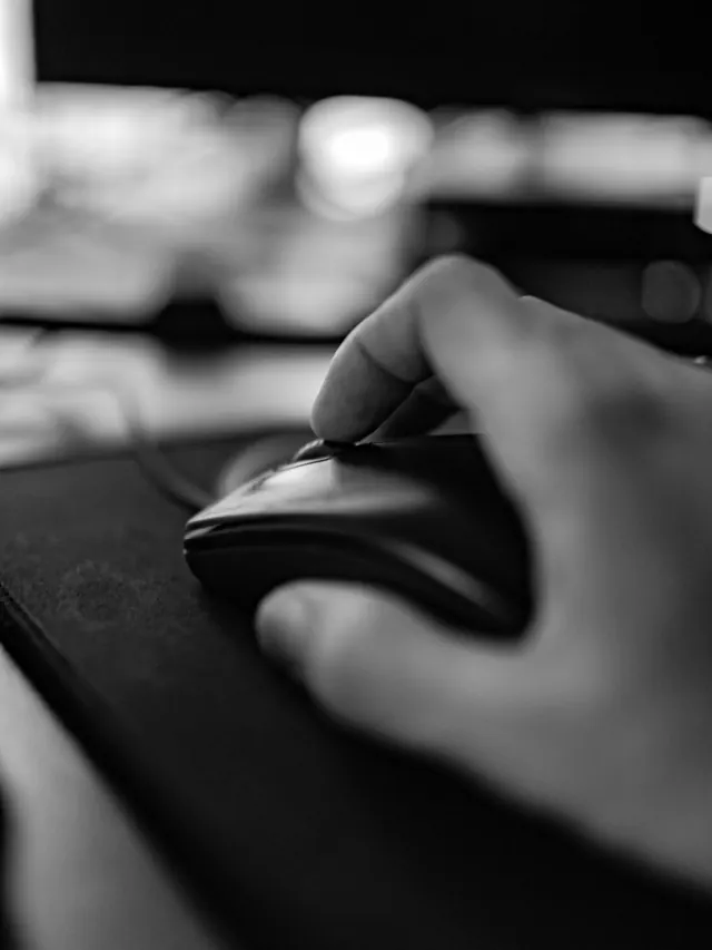 Close-up of a hand clicking a generic mouse; illustrative photo