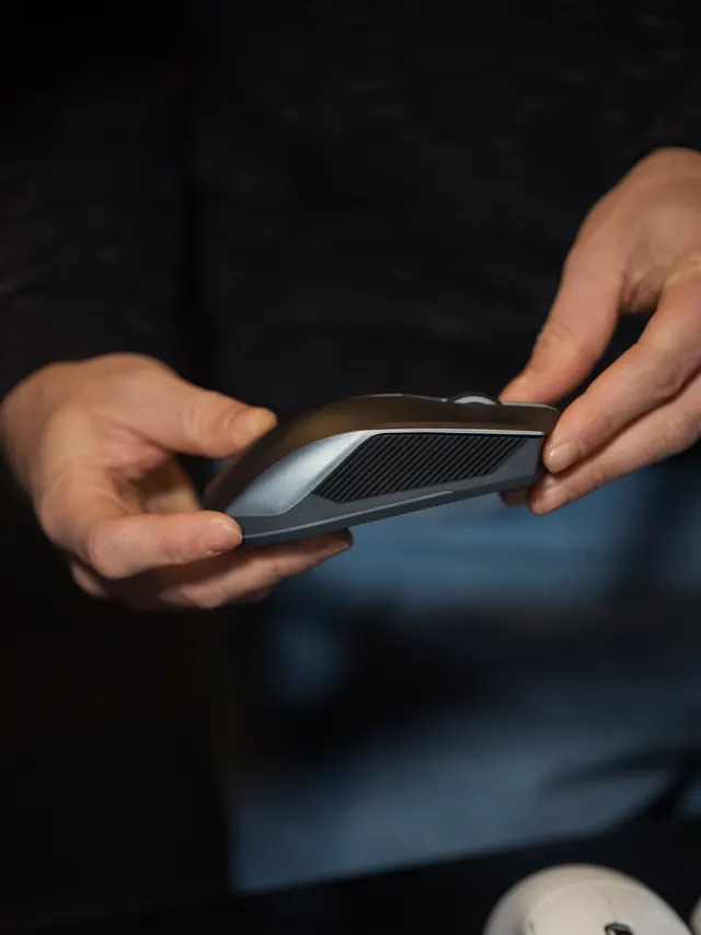Hands inspecting the shape of a generic computer mouse; illustrative photo