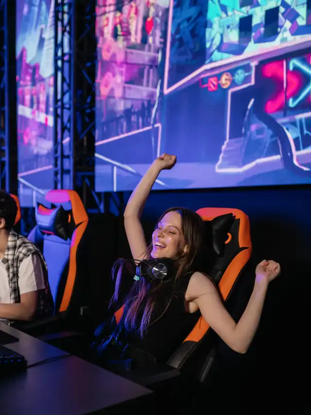 Woman celebrating at a neon gaming setup; illustrative stock photo