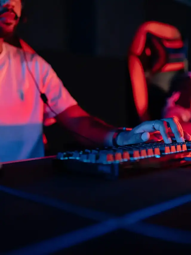 Esports player using a mechanical keyboard under red and blue lighting