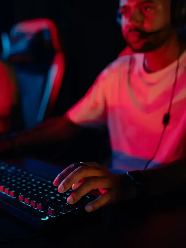 Headset-wearing gamer reaching across a mechanical keyboard