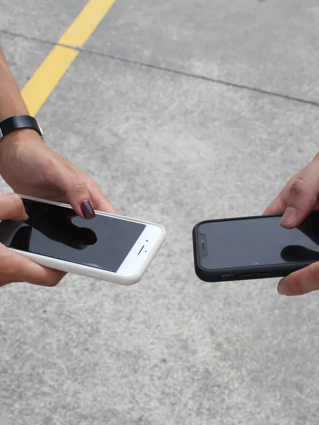 Two people holding smartphones side by side for a direct comparison