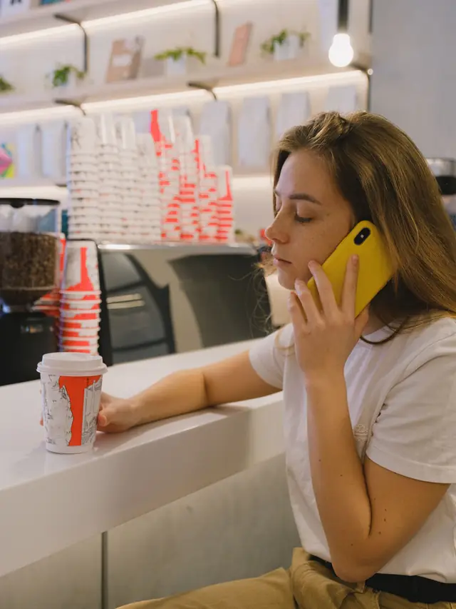 Woman using a yellow smartphone at a cafe during a real-world retest