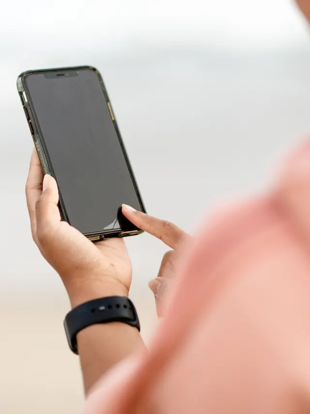 Woman closely reviewing a smartphone screen outdoors