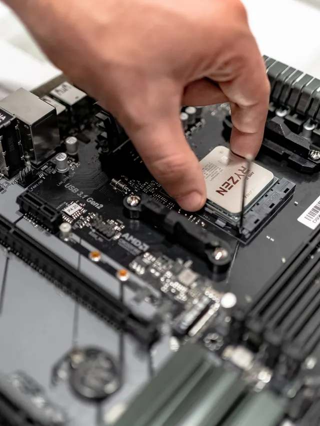 Hand placing an AMD Ryzen processor onto a motherboard socket
