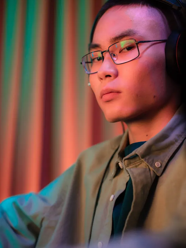 Serious man wearing eyeglasses and headphones in front of colorful curtains