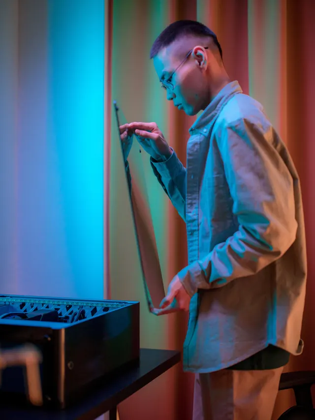 Man inspecting a panel beside his open desktop computer at home
