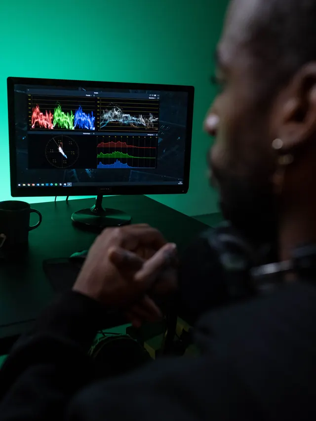 Man studying diagnostic graphs on a monitor in a dark room