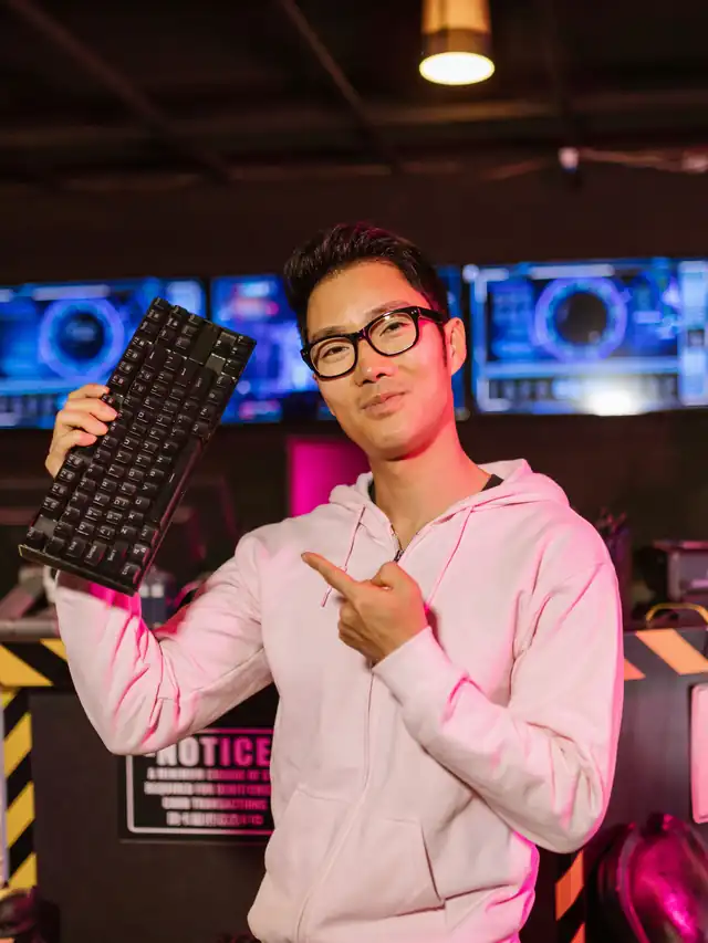 Gamer holding up a compact keyboard in a colorful gaming room
