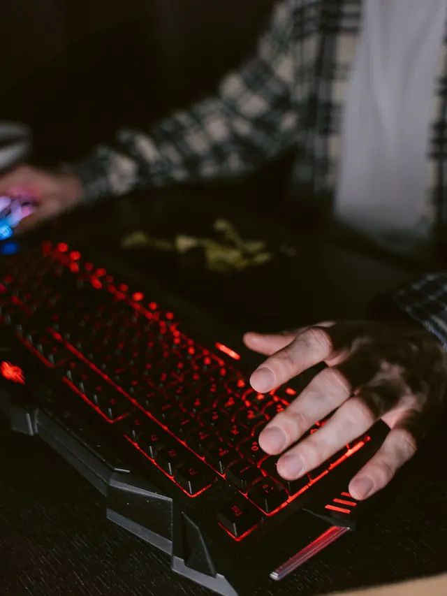 Person testing combinations on a red-backlit keyboard beside a controller