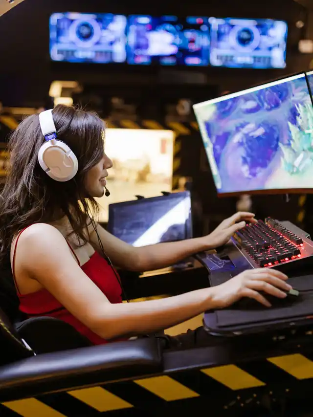 Gamer in a red top and white headset playing at a keyboard