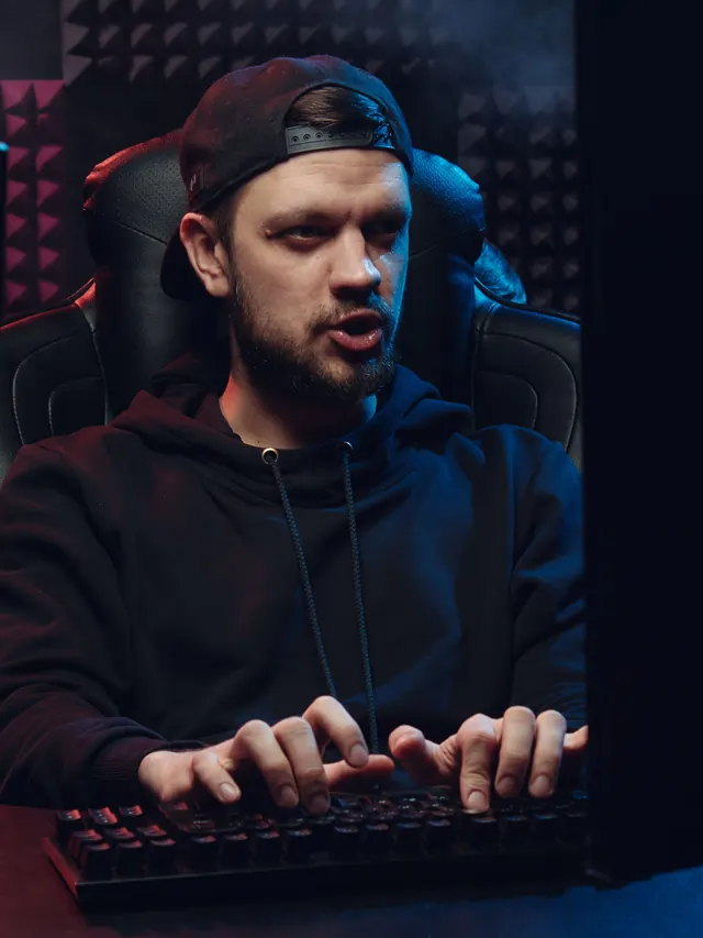 Bearded gamer actively pressing keys between two monitors; illustrative stock photo, not the reviewed Razer model