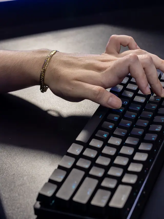 Hand deliberately pressing several keys on a mechanical keyboard; illustrative stock photo