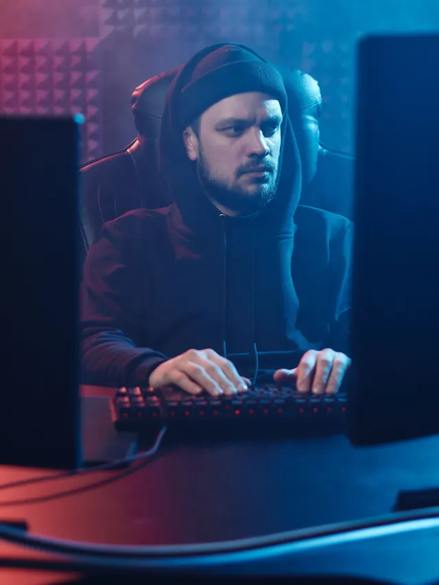 Bearded gamer typing between two monitors; illustrative stock photo, not the reviewed Razer model