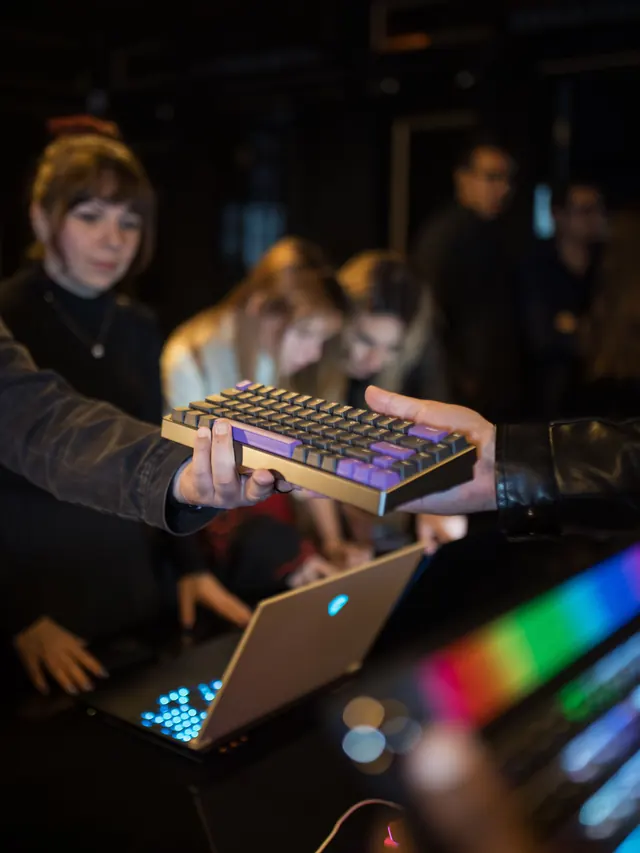 People inspecting a compact mechanical keyboard at a technology event; illustrative stock photo
